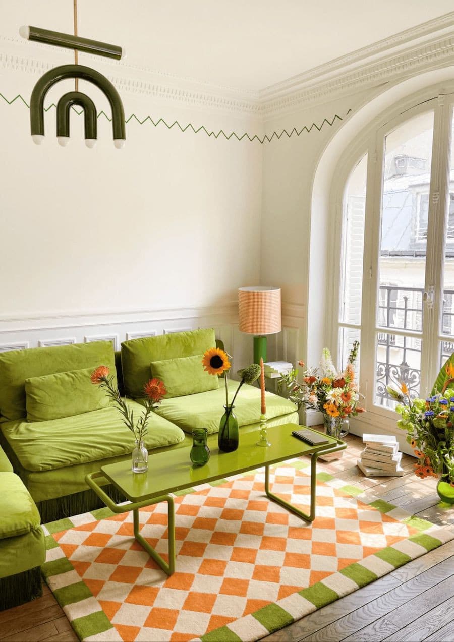 Living vintage moderno con gran sofá verde, mesa de centro y alfombra estilo "ajedrez" color blanco y naranjo