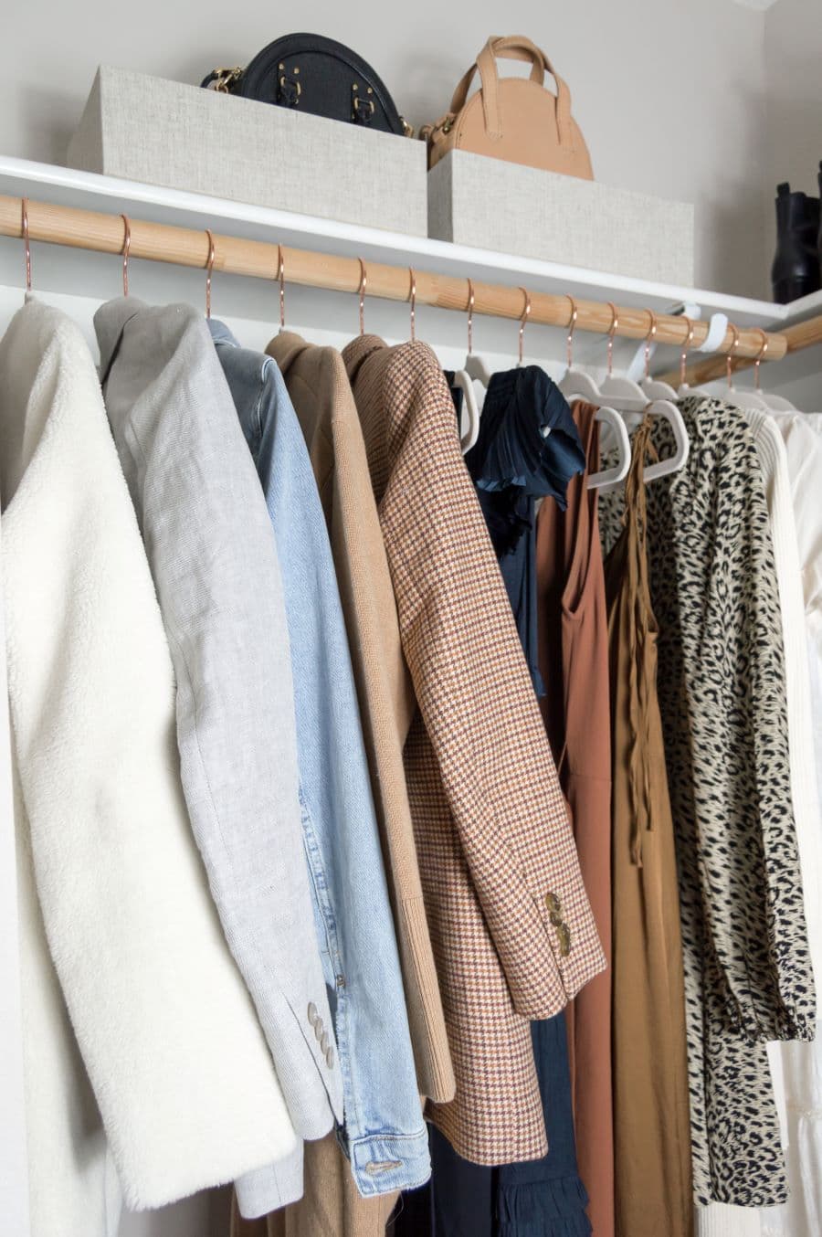 Walk in closet pequeño. Barra de madera con colgadores con ropa organizada por color.