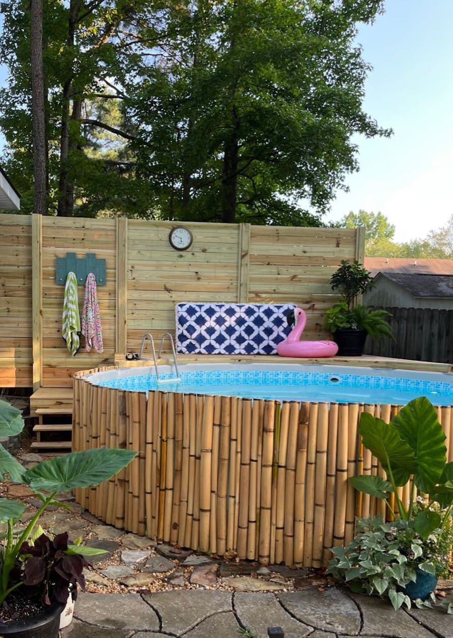 Piscina redonda estructural con cierre de bambú. Deck de madrera con escaleras y un colgador para toallas.